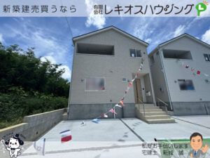 グレー外壁の2階建て外観。2階にインナーバルコニー、前面は駐車場