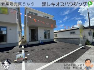 白と茶のツートン外壁の新築2階建て住宅と広い駐車スペース