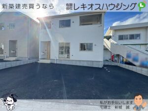 白い外壁の2階建て外観。インナーバルコニーと広い駐車スペース