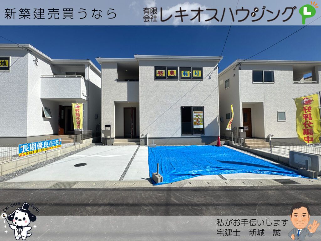 白い外壁の3号棟外観と前面のコンクリート駐車場