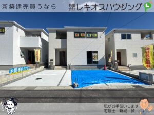 白い外壁の3号棟外観と前面のコンクリート駐車場