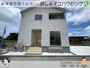 白い外壁の2階建て外観。木目調の玄関ドアとインナーバルコニー