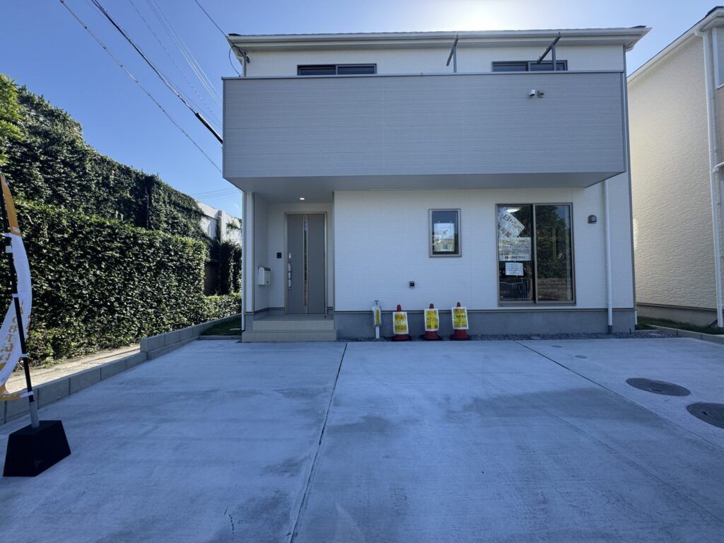 グレーと白の2階建て住宅の外観。玄関前にオープンハウスの看板