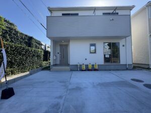 グレーと白の2階建て住宅の外観。玄関前にオープンハウスの看板