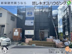 足場と養生シートに覆われた建築中の建物と積まれた資材
