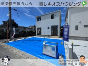 白い外壁の2階建て外観。前面の駐車スペースにブルーシート