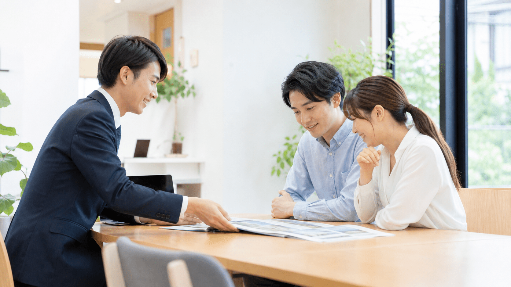 オフィスで担当者が夫婦に資料を広げて説明している様子