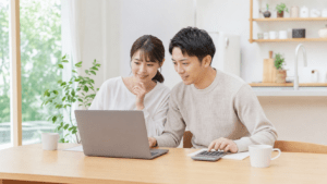 ノートパソコンと電卓で住宅ローンを試算する夫婦
