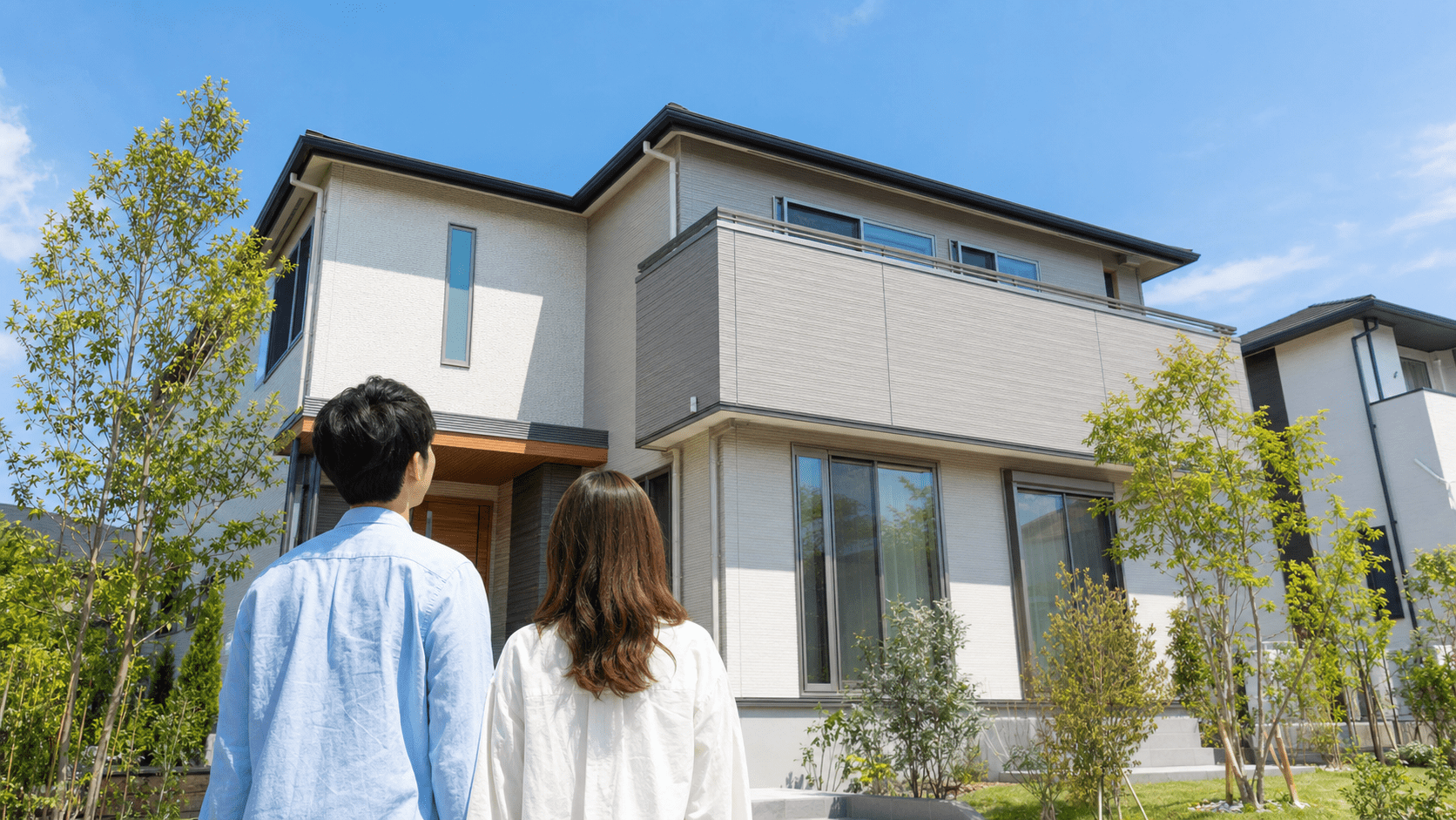 新築住宅を見上げる夫婦の後ろ姿