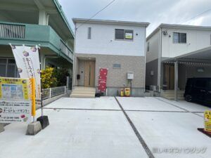ベージュと白の外壁の2階建て。建物の前面に駐車スペースがある外観です