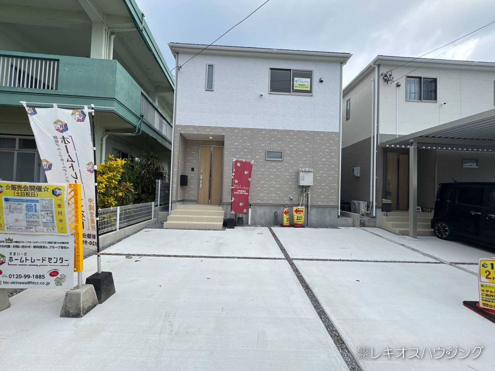ベージュと白の外壁の2階建て。建物の前面に駐車スペースがある外観です